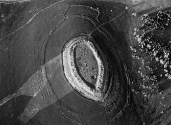 Oblique aerial view centred on the cropmarks of roundhouses  and a rectangular enclosure within the White Caterthun fort with the remains of an unenclosed settlement adjacent, looking to the NNE.