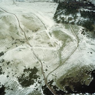 Scanned image of oblique aerial view of Castle Knowe in the Pentland Hills, centred on the remains of the trenches with the palisaded settlement and rig adjacent, taken from the SSW.