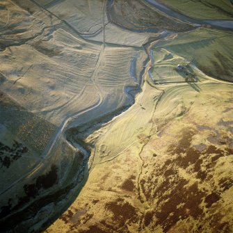 Scanned image of oblique aerial view centred on the remains of the farmstead, buildings, rig and cultivation terraces with the remains of the possible settlement and enclosure adjacent, taken from the ENE.