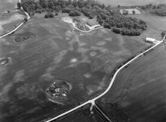 Oblique aerial view centred on the cropmarks of the timber hall, ring ditch, enclosures and pits at Mondobbo House, looking to the SE.