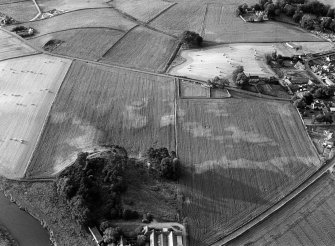 Oblique aerial view centred on the cropmarks of the barrow at Boat of Hatton with the burial ground adjacent, looking to the N.