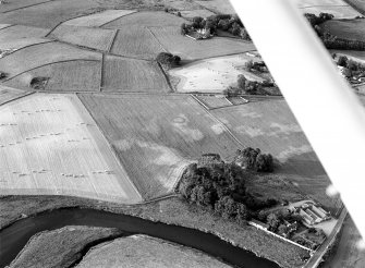 Oblique aerial view centred on the cropmarks of the barrow at Boat of Hatton with the burial ground adjacent, looking to the NNE.