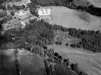 Oblique aerial view centred on the cropmarks of the pit alignment and timber hall with Crathes Castle and gardens adjacent, looking to the NNW.

