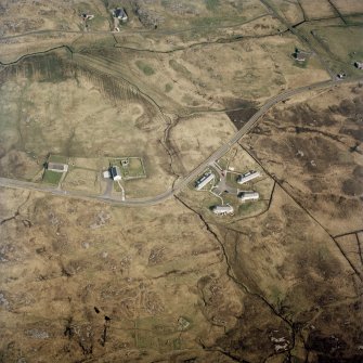 Oblique aerial view centred on the church, burial ground and manse with the houses adjacent, taken from the SW.