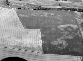 Oblique aerial view centred on the cropmarks of the unenclosed settlement, ring ditch, soutterains and pits at Burnhead of Mondobbo, looking to the SSE.