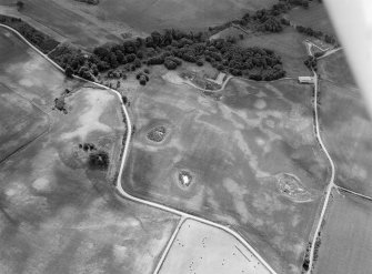 Oblique aerial view centred on the cropmarks of the timber hall, ring ditch, enclosures and pits at Mondobbo House, looking to the SSE.
