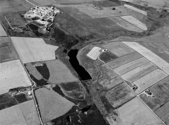 Oblique aerial view centred on the Den of Boddam reservoir, flint mines and lithic working site with RAF Buchan radar station adjacent, looking to the SSW.