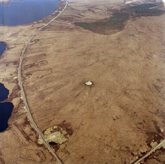 Oblique aerial view centred on the remains of the chambered cairn, taken from the WSW.