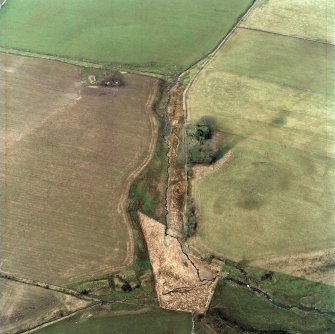 Oblique aerial view centred on the remains of the chapel and graveyard, taken from the SE.