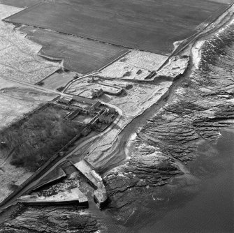 Oblique aerial view of the farmsteading, harbour and the remains of the windmill, cottage and broch taken from the E