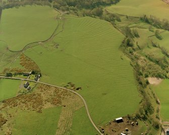 Oblique aerial view centred on the remains of the rig, small cairns, hut-circles and quarry, taken from the ESE.