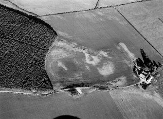 Oblique aerial view centred on the cropmarks of an enclosure at Nether Bogside and Upper Manbeen with the farmstead adjacent, looking to the ESE.