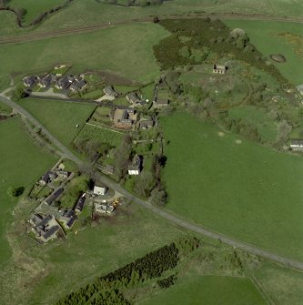 Oblique aerial view of the village centred on the burial-ground, manse and the remains of the church with the farmsteading adjacent, taken from the S.