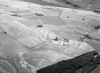 Oblique aerial view centred on the cropmarks of an unenclosed settlement, ring ditches, enclosures and pits at Craigston Castle, looking to the SSW.