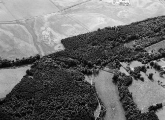 Oblique aerial view centred on Craigston Castle with the cropmarks of an unenclosed settlement, ring ditches, enclosures and pits adjacent, looking to the SW.
