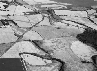 Oblique aerial view centred on the cropmarks of the unenclosed settlement, ring ditches, souterrain, pit alignment, rig and linear features at Arrat's Mill, looking to the ENE.