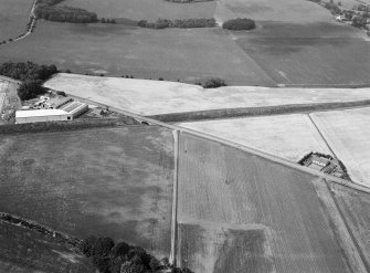 Oblique aerial view centred on the cropmarks of an unenclosed settlement, linear features, souterrains and pits at Gilrivie, looking to the N.