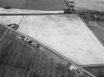 Oblique aerial view centred on the cropmarks of an unenclosed settlement, linear features, souterrains and pits at Gilrivie, looking to the NNW.