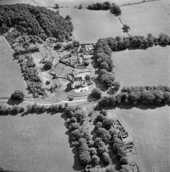 Oblique aerial view centred on the country house with the stables adjacent, taken from the NW.