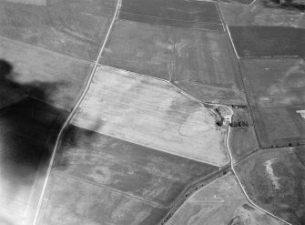 Oblique aerial view centred on the cropmarks of a circular enclosure at Myreside with the farmstead adjacent, looking to the ENE.