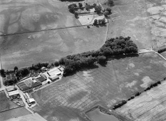 Oblique aerial view centred on the cropmarks of the fort, ring ditch and rig at Mains of Edzell with the farmstead adjacent, looking to the W.