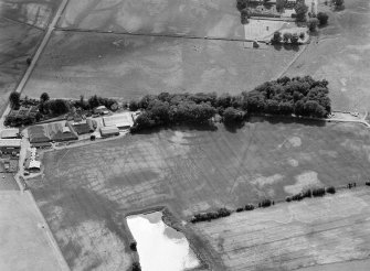 Oblique aerial view centred on the cropmarks of the fort, ring ditch and rig at Mains of Edzell with the farmstead adjacent, looking to the SW.