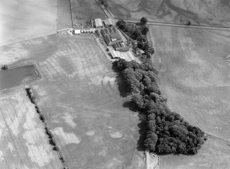 Oblique aerial view centred on the cropmarks of the fort, pits and rig at Mains of Edzell with the farmstead adjacent, looking to the SSE.