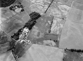 Oblique aerial view centred on the cropmarks of the fort, ring ditch, pits and rig at Mains of Edzell with the farmstead adjacent, looking to the NNW.