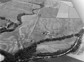 Oblique aerial view centred on the cropmarks of the unenclosed settlement, ring ditches, pits and rig with Stracathro Roman Fort and Temporary Camp adjacent at Smiddyhill, looking to the SW.