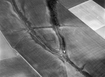 Oblique aerial view centred on the cropmarks of a rectlinear enclosure, possible souterrains, pits and rig at Chapel Knap, looking to the SE.