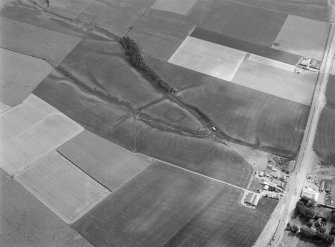 Oblique aerial view centred on the cropmarks of a rectlinear enclosure, possible souterrains, pits and rig at Chapel Knap, looking to the SE.