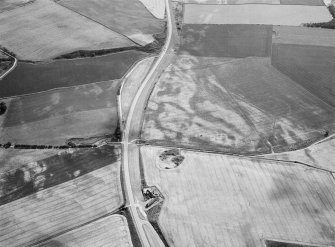 Oblique aerial view centred on the cropmarks of the pit defined cursus and linear features at Purlieknowe, looking to the SW.
