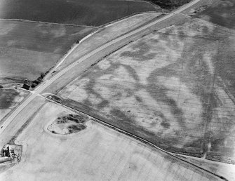 Oblique aerial view centred on the cropmarks of the pit defined cursus and linear features at Purlieknowe, looking to the SW.