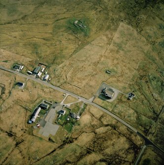Oblique aerial view centred on the church and school with the mission hall and remains of the chambered cairn and sheepfold adjacent, taken from the WSW.