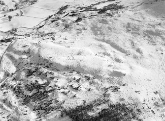 Oblique aerial view centred on the remains of hut circles and clearance cairns at Wester Clune, looking to the SSE.