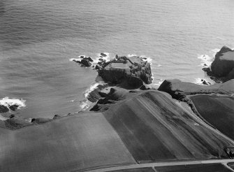 Oblique aerial view centred on the remains of the earthwork and castle at Dunnottar, looking to the ESE.