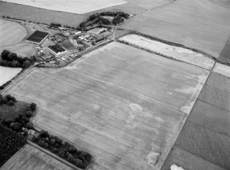 Oblique aerial view centred on the remains of ring ditches at Longmorn with the distillery adjacent, looking to the ENE.
