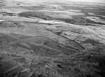 Distant oblique aerial view centred on the remains of the Roman temporary camp and cairnfield at Raedykes and Garrison Hill, looking to the SSW.