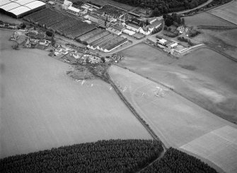 Oblique aerial view centred on the excavation of the earthwork and enclosure at Thomshill with Glenlossie distillery adjacent, looking to the ESE.
