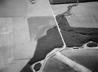 Oblique aerial view centred on the cropmarks of the unenclosed settlement, ring ditches and enclosures at Lower Auchenreath with Dallachy airfield adjacent, looking to the SE.