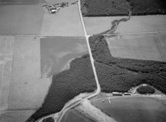 Oblique aerial view centred on the cropmarks of the unenclosed settlement, ring ditches and enclosures at Lower Auchenreath with Dallachy airfield adjacent, looking to the SE.