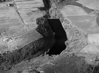 Oblique aerial view centred on the Den of Boddam reservoir, flint mines and lithic working site, looking to the NNE.