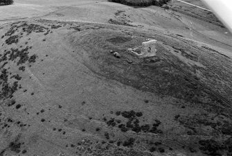 Oblique aerial view centred on the remains of the tower house and fort at Dunideer, looking to the SSE.