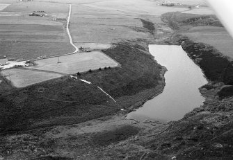 Oblique aerial view centred on the Den of Boddam reservoir, flint mines and lithic working site, looking to the NNE.