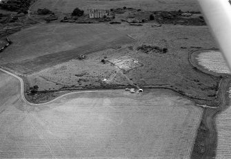 Oblique aerial view centred on the remains of the recumbent stone circle and dovecot, looking to the SW.