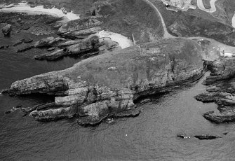 Oblique aerial view centred on the remains of the promontory fort at Green Castle, Portknockie, looking to the SE.