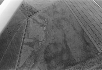 Oblique aerial view centred on the cropmarks of the unenclosed settlement, ring ditches, souterrains and rig at Westside, looking to the WNW.