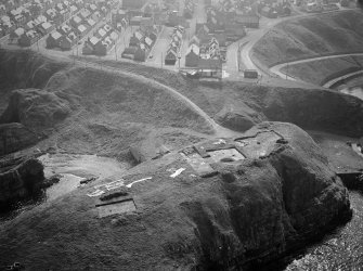 Oblique aerial view centred on the excavation of the promontory fort at Green Castle, Portknockie with the village adjacent, looking to the S.