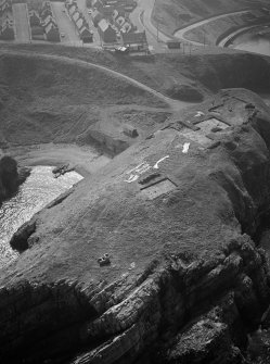 Oblique aerial view centred on the excavation of the promontory fort at Green Castle, Portknockie, looking to the SSW.