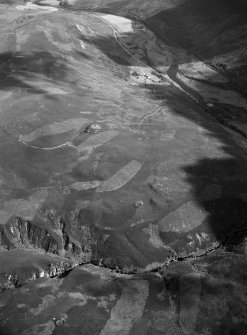 Oblique aerial view centred on the remains of Kilphedir Broch, field system and hut circles, looking to the SE.